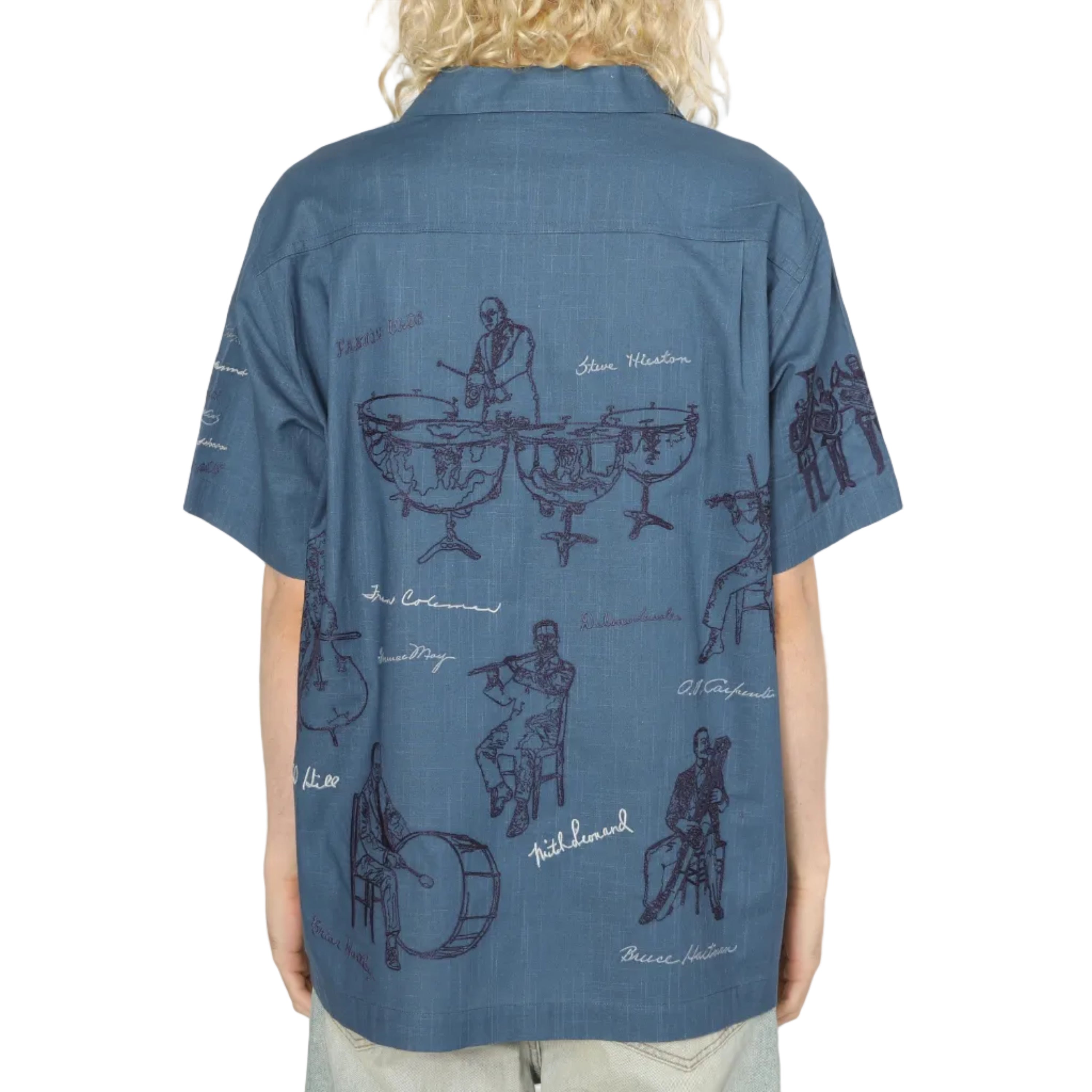 Person wearing a blue shirt with black graphics on the back, standing against a white background