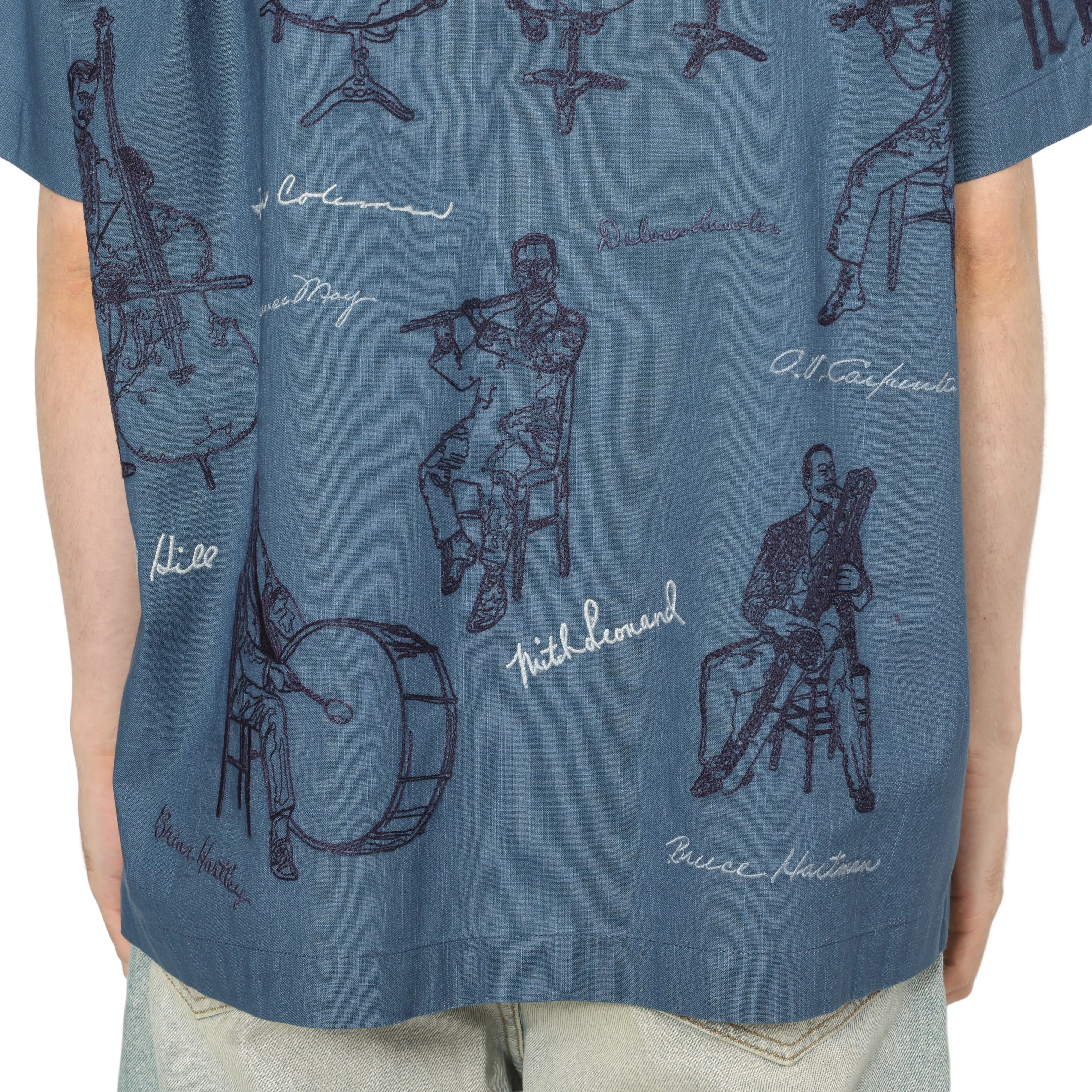 Blue shirt with musical instrument illustrations and text on a beige background