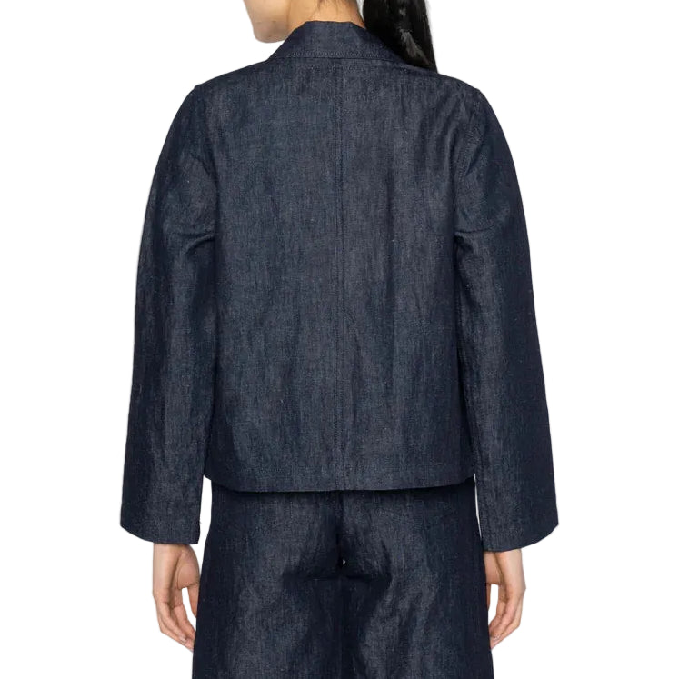 Person wearing a dark denim jacket and pants on a white background
