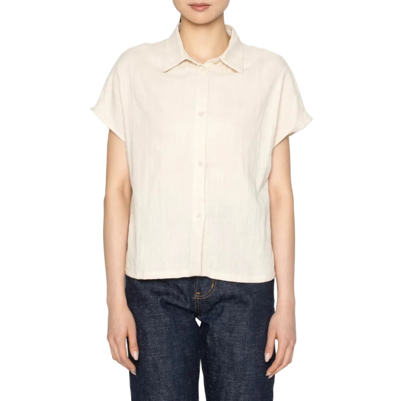 Woman wearing a beige shirt and dark jeans on a white background
