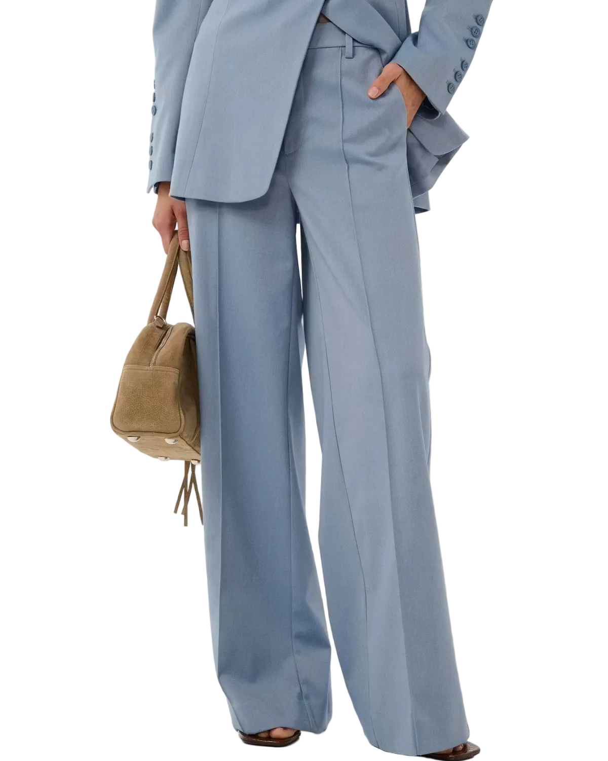 Person wearing a light blue suit with wide-leg pants holding a brown handbag on a white background