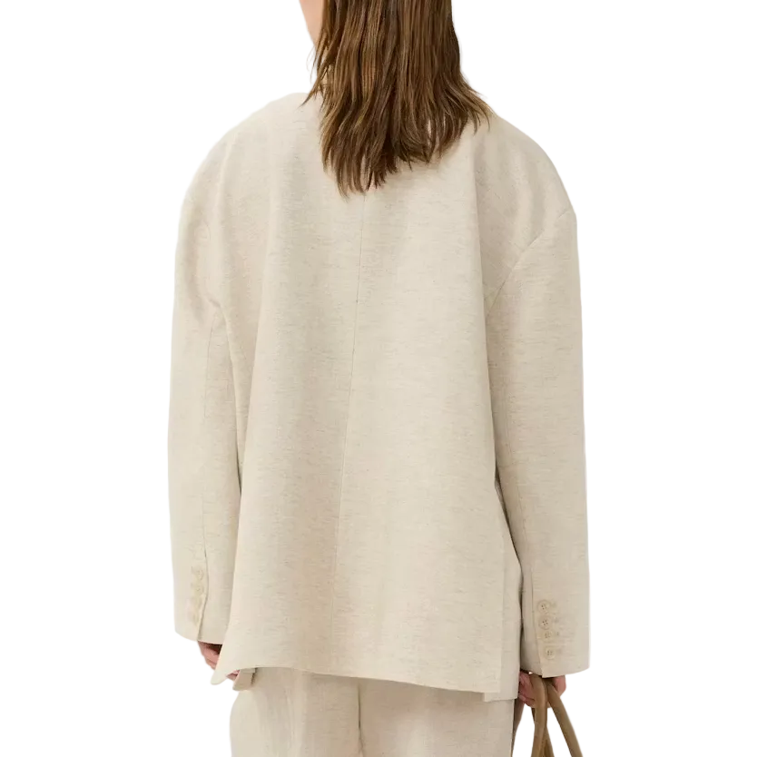 Person wearing a beige suit holding a brown handbag on a white background