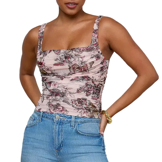 Woman wearing a patterned tank top and blue jeans against a gray background