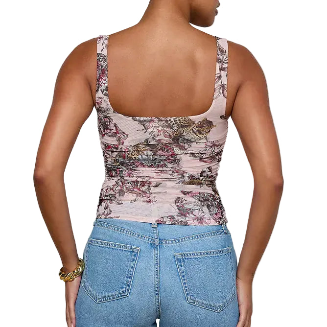 Woman wearing a floral tank top and blue jeans on a plain background