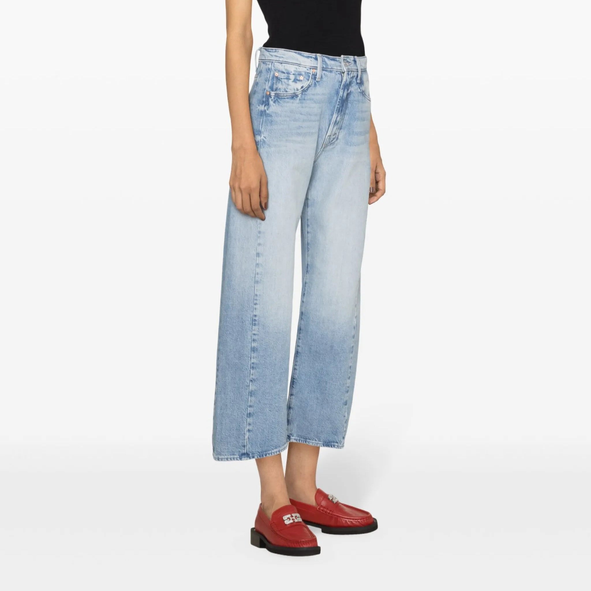 Woman wearing a black tank top and light blue jeans on a white background