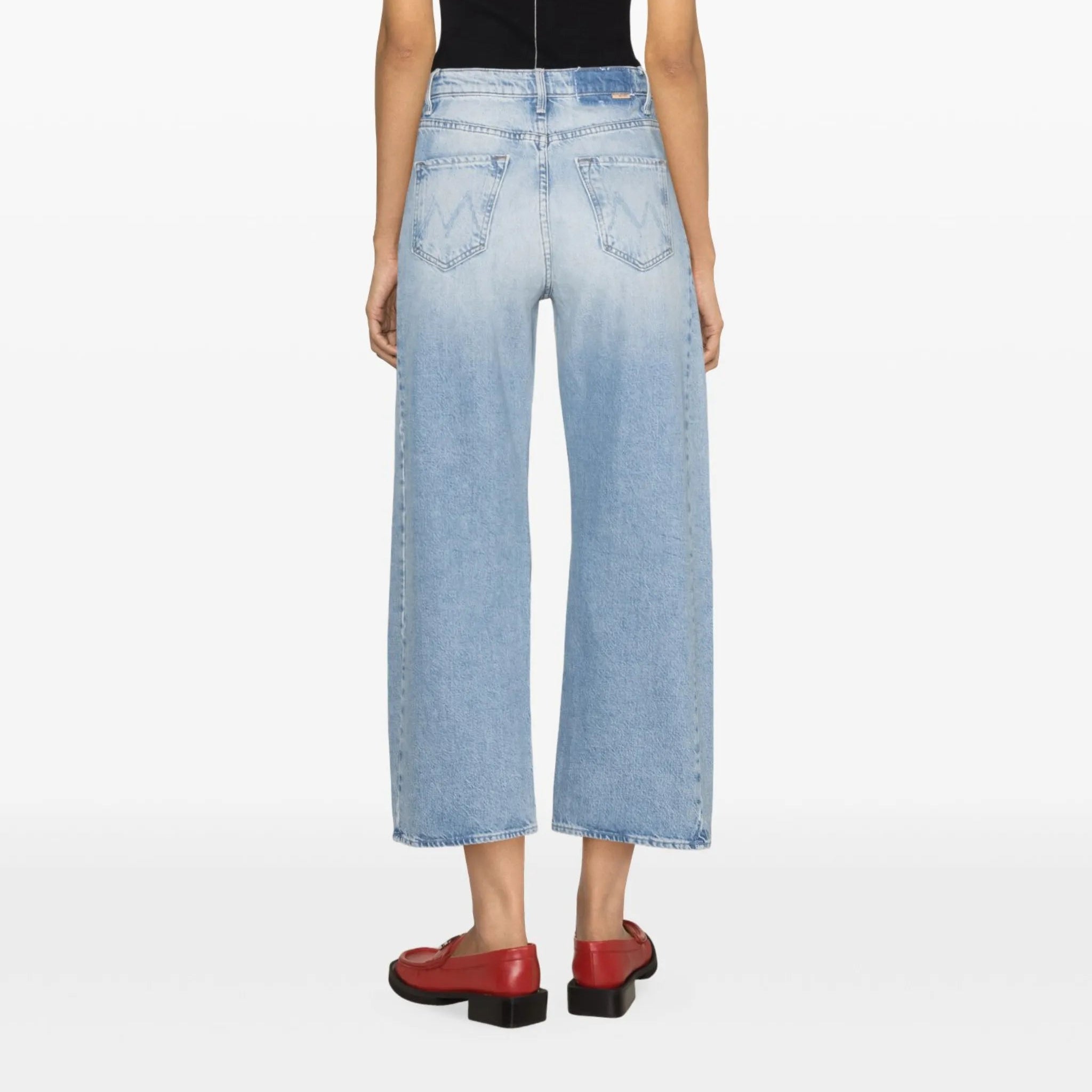 Person wearing a black tank top and light blue jeans on a white background