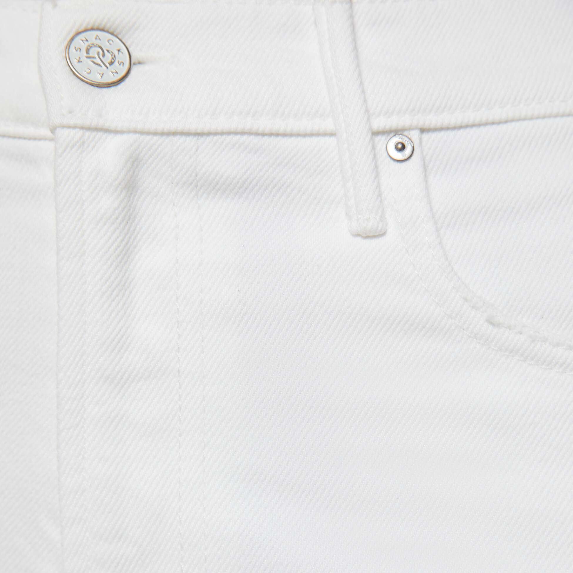 Close-up of white denim fabric with button and stitching details