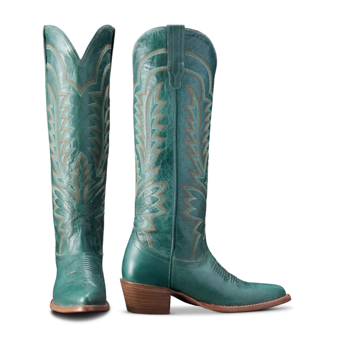 Pair of teal cowboy boots with decorative patterns on a white background