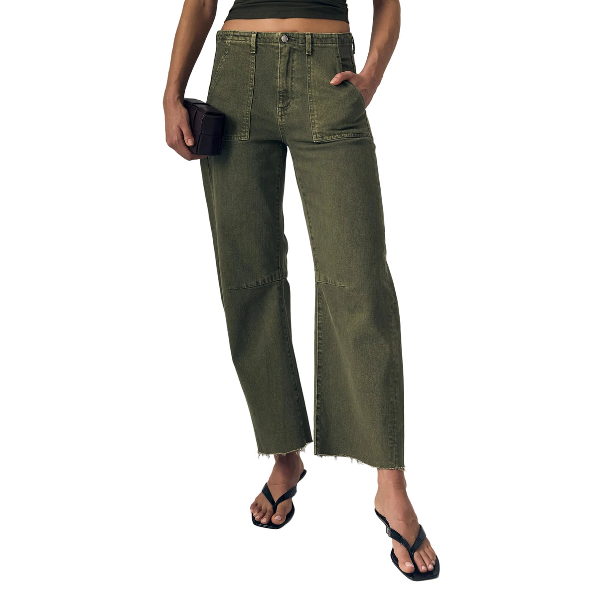 Woman wearing a green top and wide-leg pants against a plain background