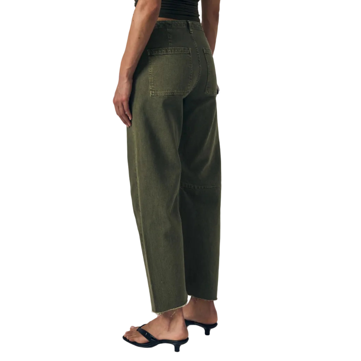 Person wearing a dark green top and green pants against a neutral background