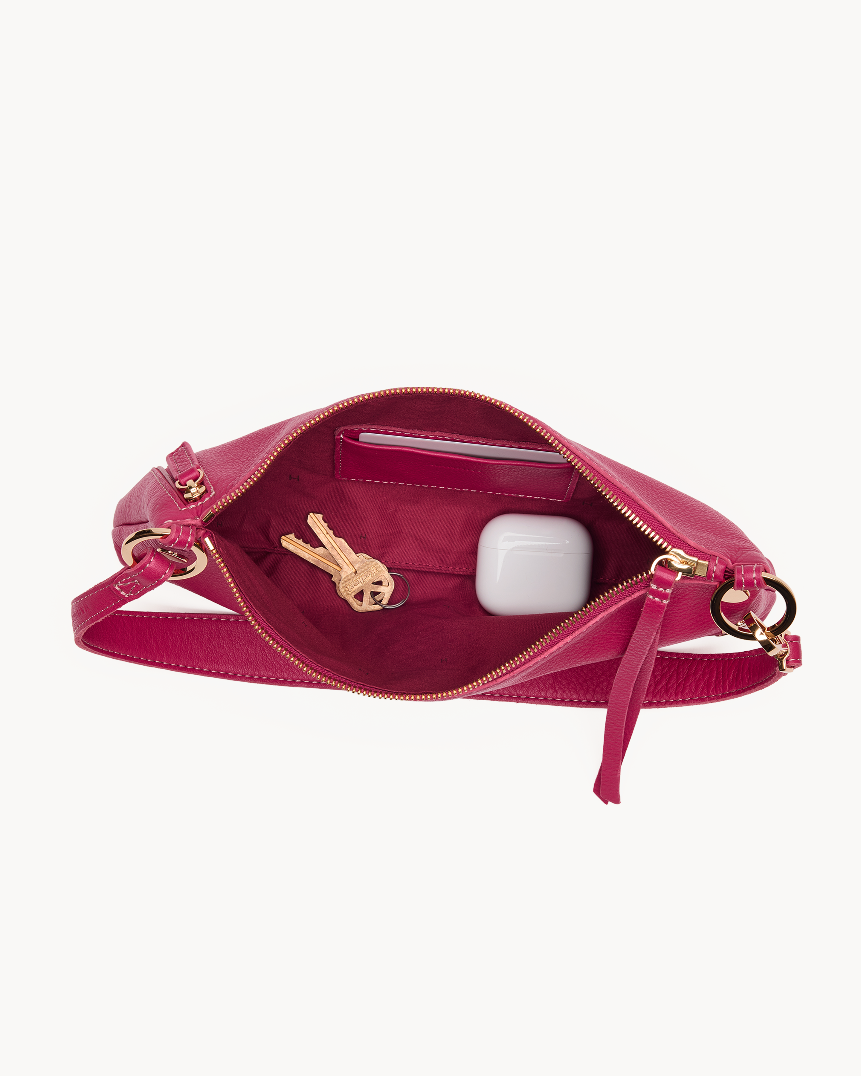 Interior view of a magenta leather convertible bag with gold accents on a white background