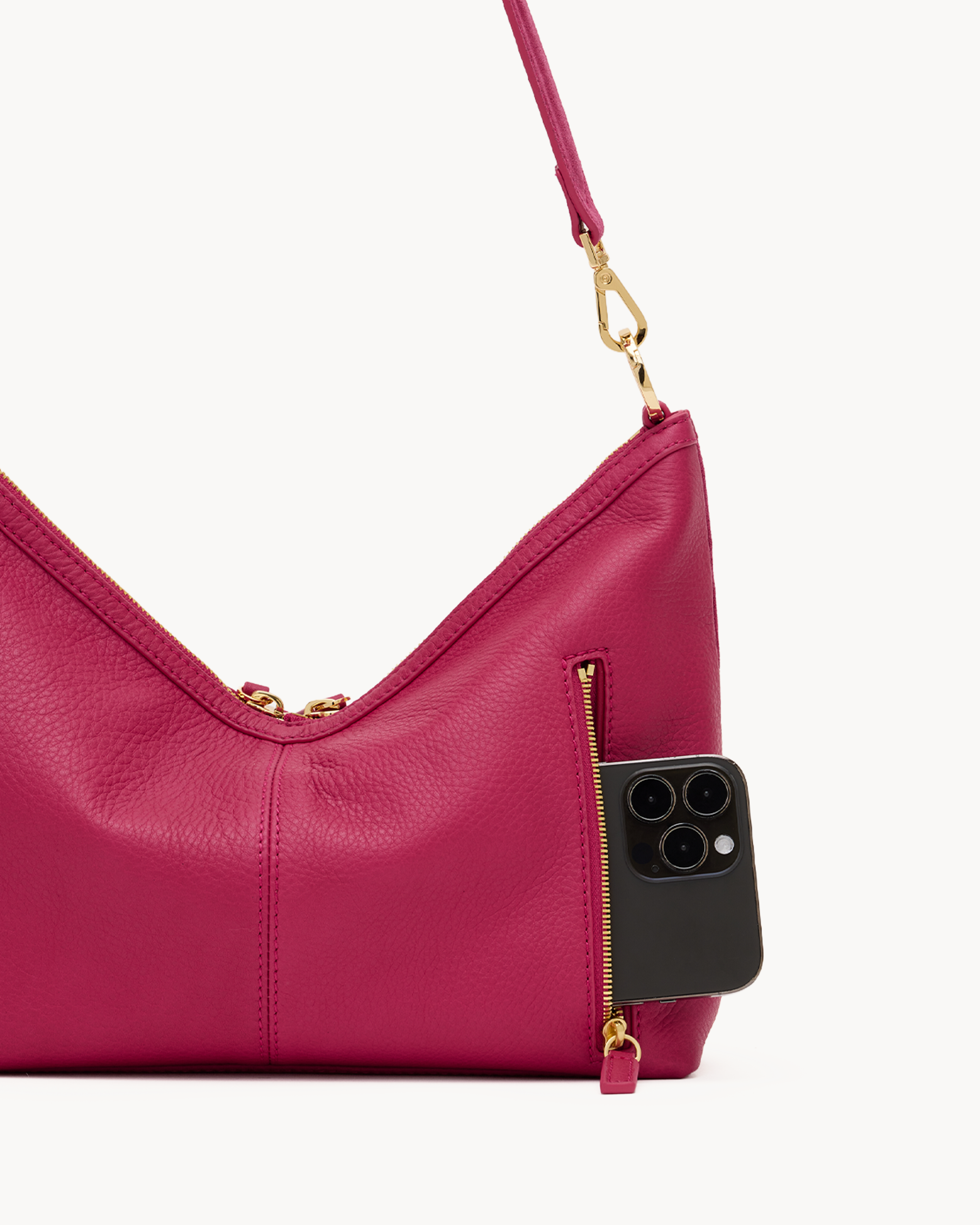 Pink leather handbag with gold accents on a white background