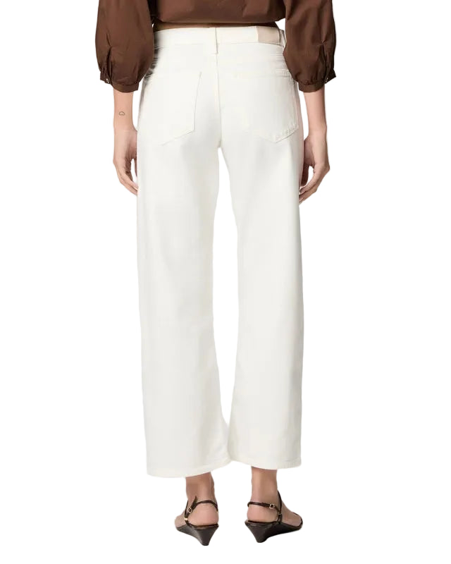 Back view of a person wearing a brown top and white pants on a plain background