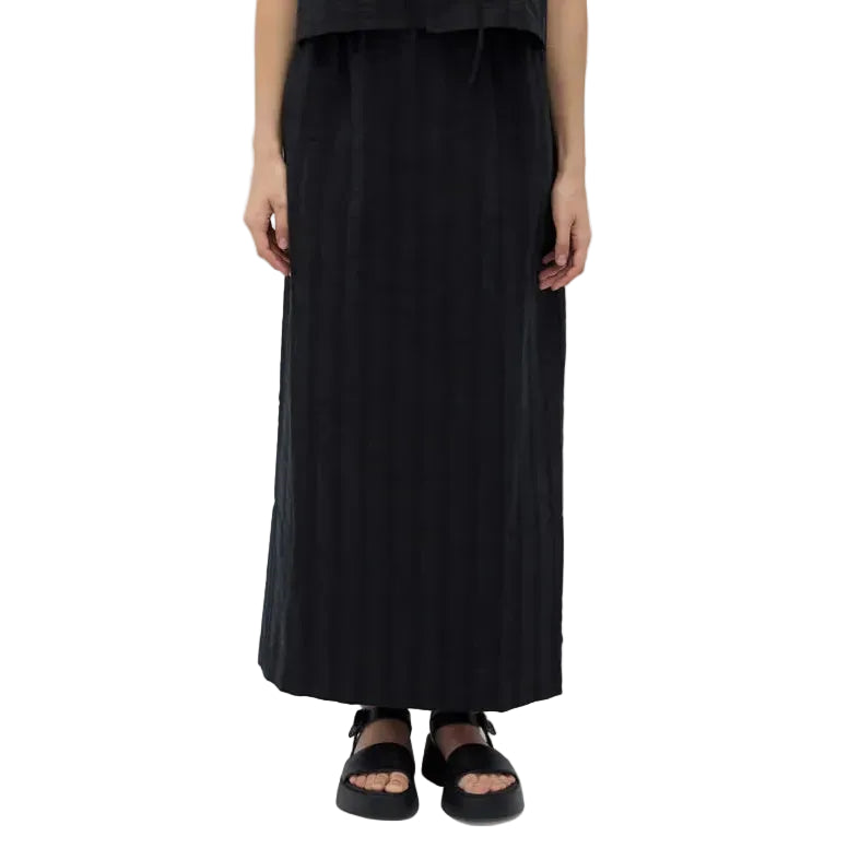 Person wearing a black midi akirt and sandals on a white background