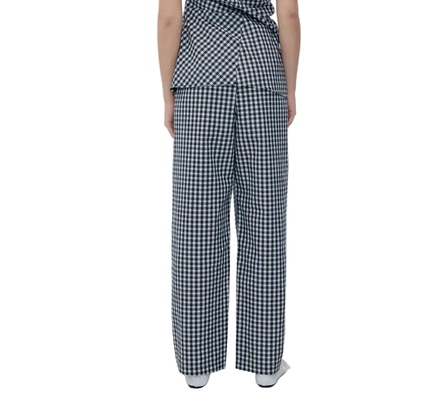 Back view of a model wearing a black and white gingham checkered outfit with wide-leg trousers, paired with white shoes, against a plain white background.