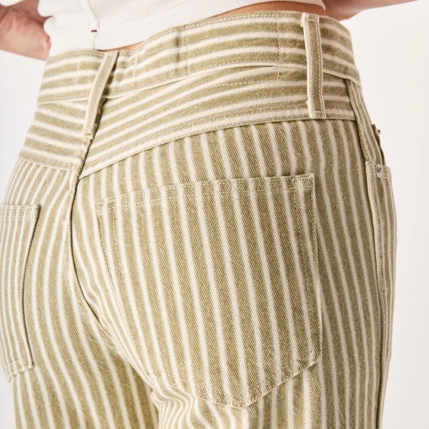 Close-up of a person wearing beige and white striped pants on a plain background