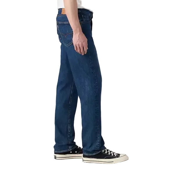 Person wearing a white t-shirt and blue jeans standing against a plain background