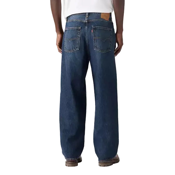 Person wearing a white t-shirt and blue jeans on a plain background