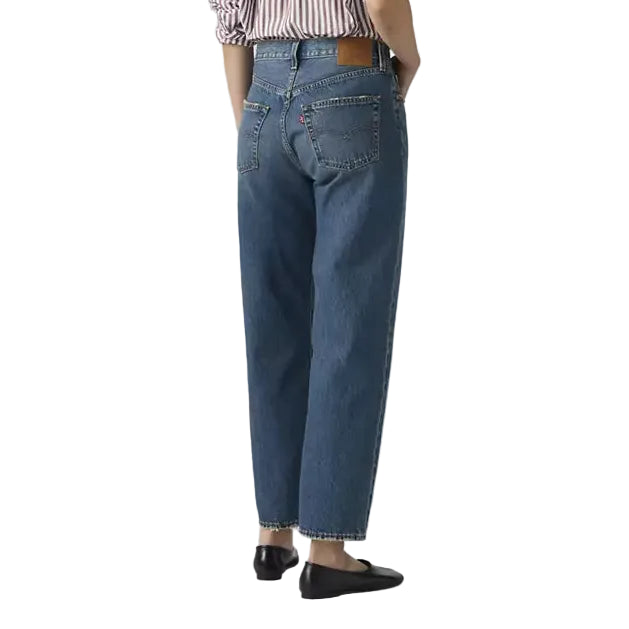 Person wearing blue jeans and a striped shirt on a plain background