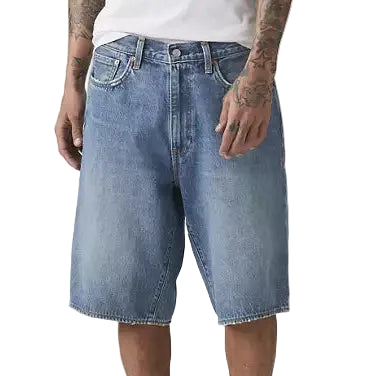 Person wearing a white t-shirt and blue denim shorts on a plain background