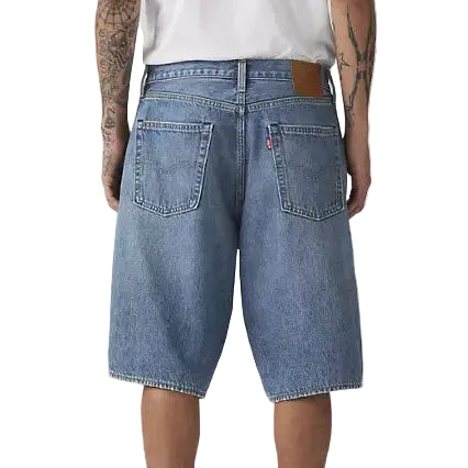 Person wearing a white t-shirt and blue denim shorts on a plain background