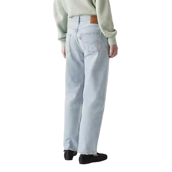 Person wearing a light green sweater and light blue jeans on a plain background
