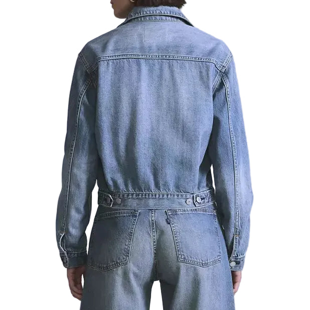 Person wearing a denim jumpsuit on a light gray background
