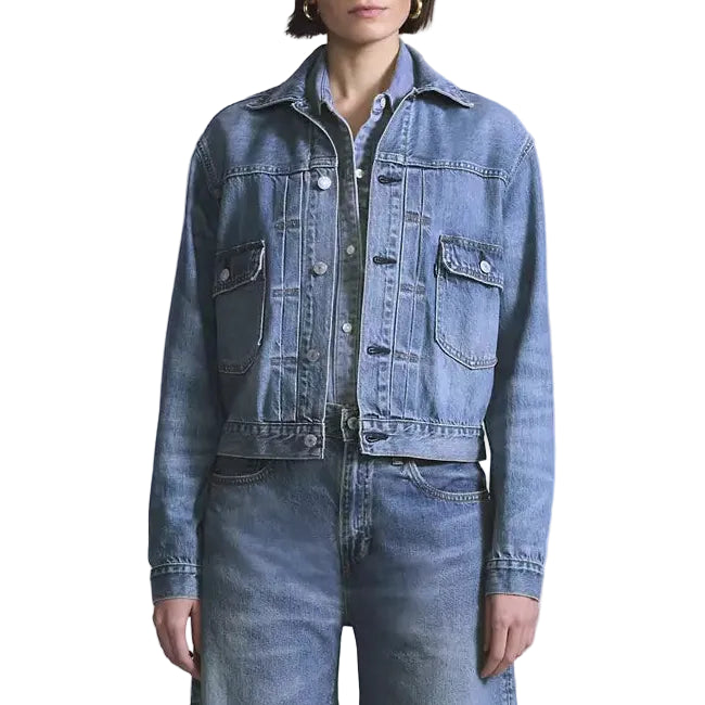 Person wearing a blue denim jacket and jeans on a white background