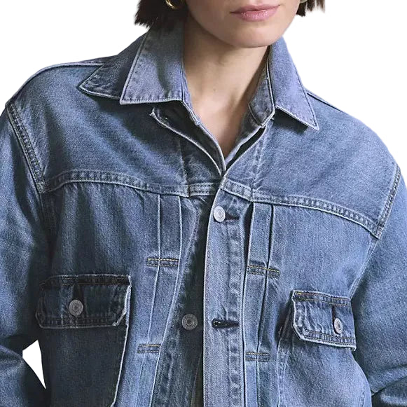 Person wearing a blue denim jacket on a plain background