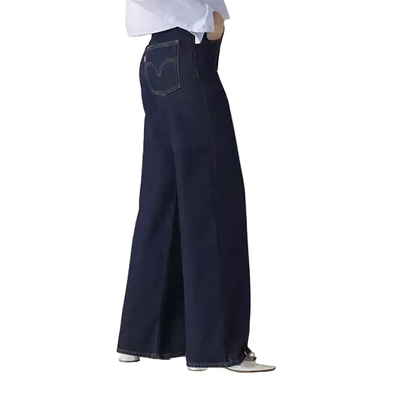 Person wearing a white shirt and dark blue wide-leg jeans on a plain background