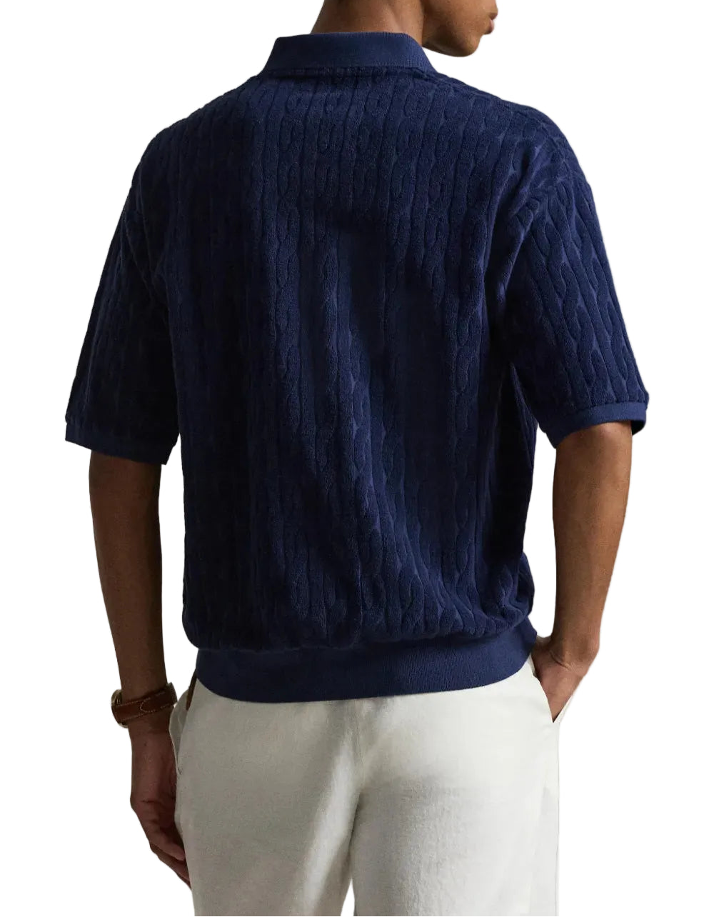 Person wearing a dark blue textured shirt and light-colored pants on a white background
