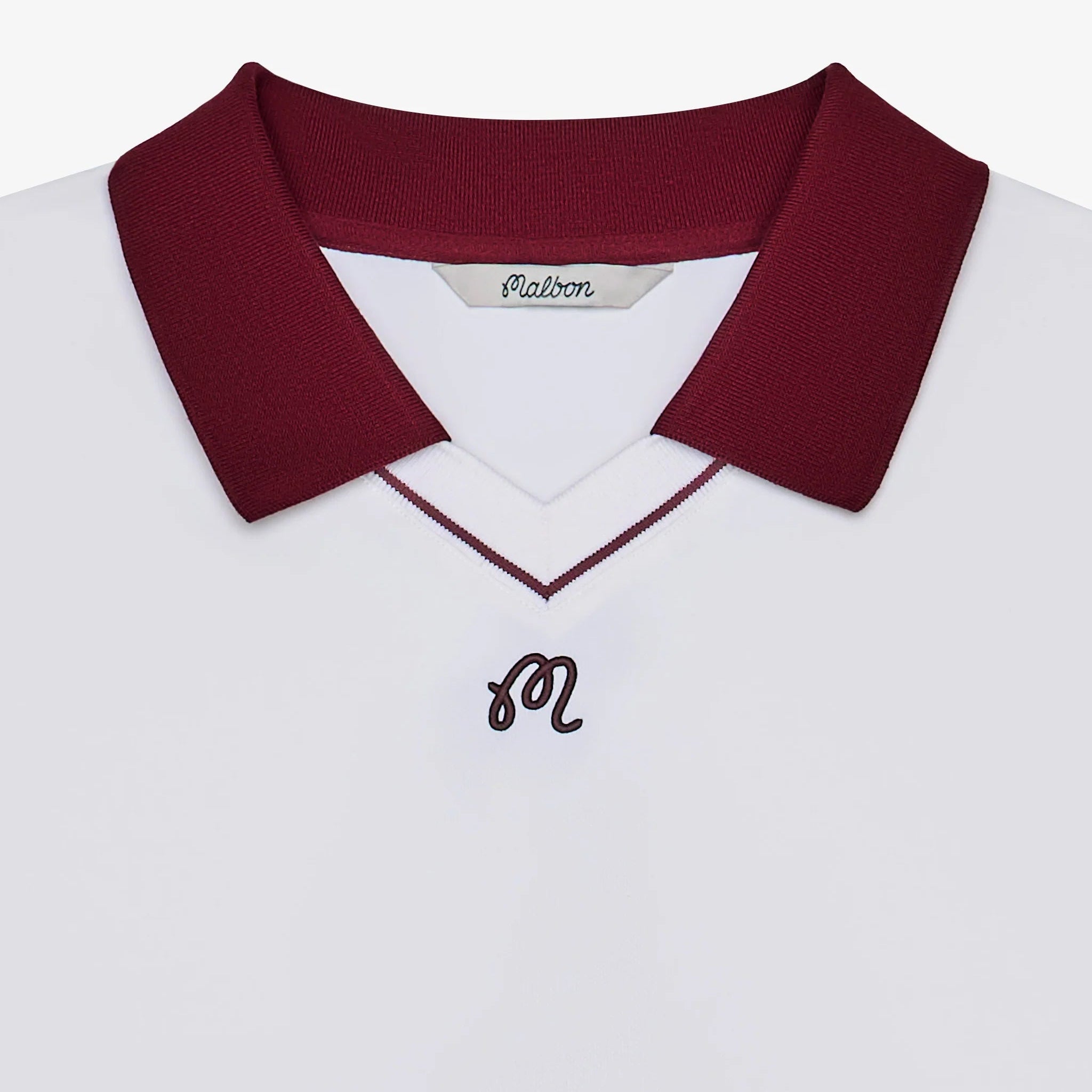 Close-up of a white polo with a maroon collar and logo at the chest on a white background