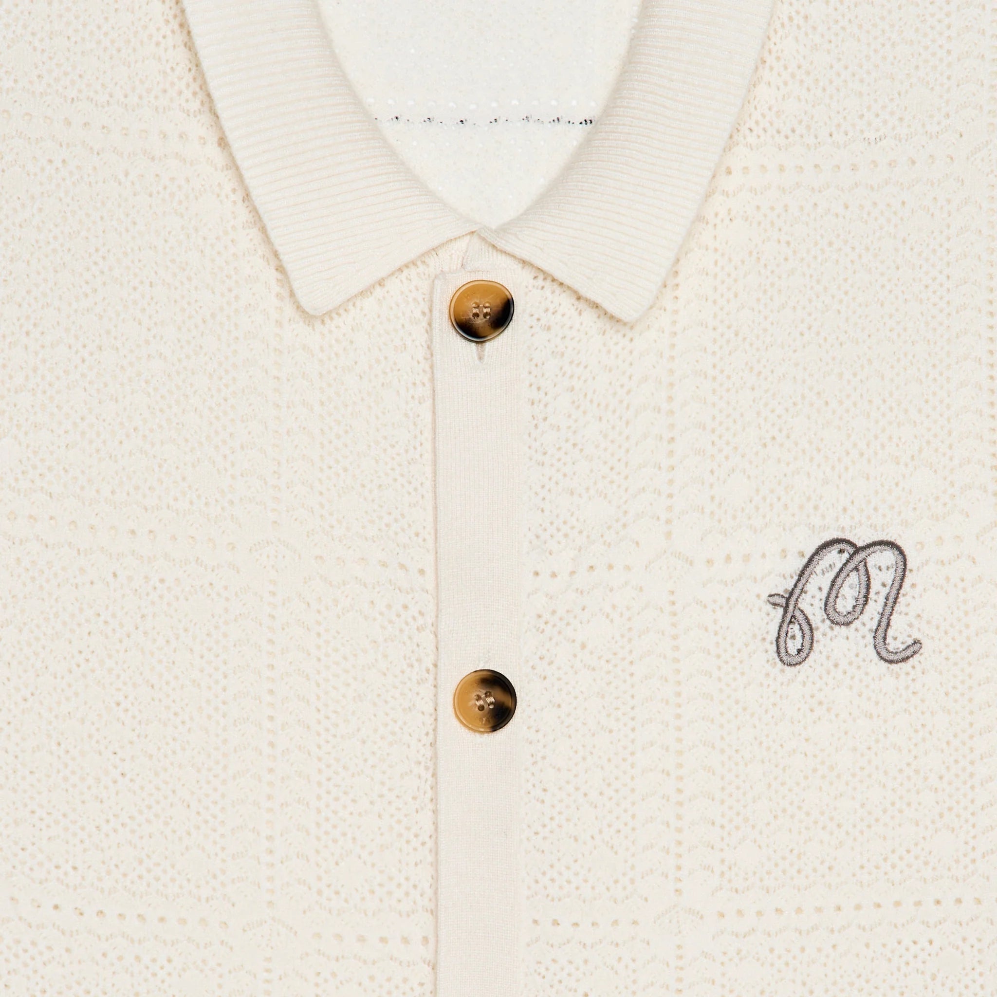 Close-up of the collar of a cream knit cardigan on a white background
