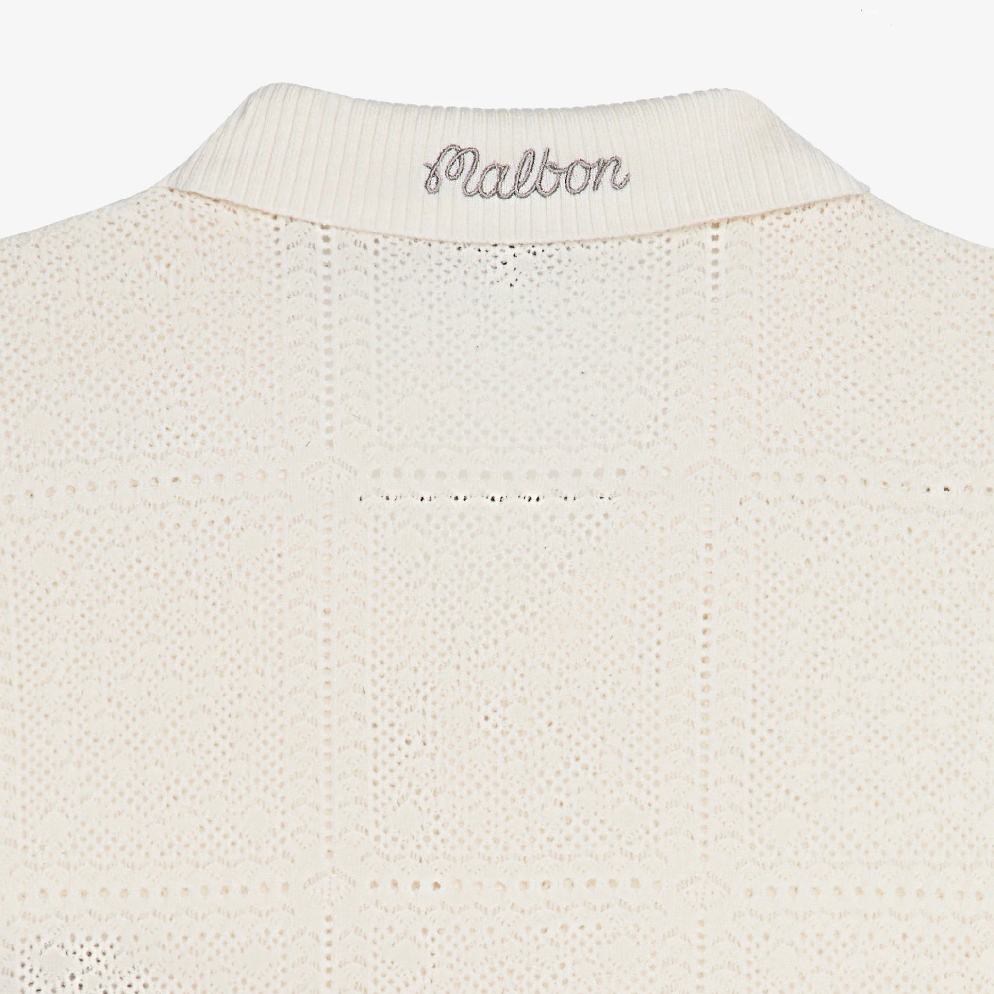 Close-up of the collar of a cream knit cardigan on a white background
