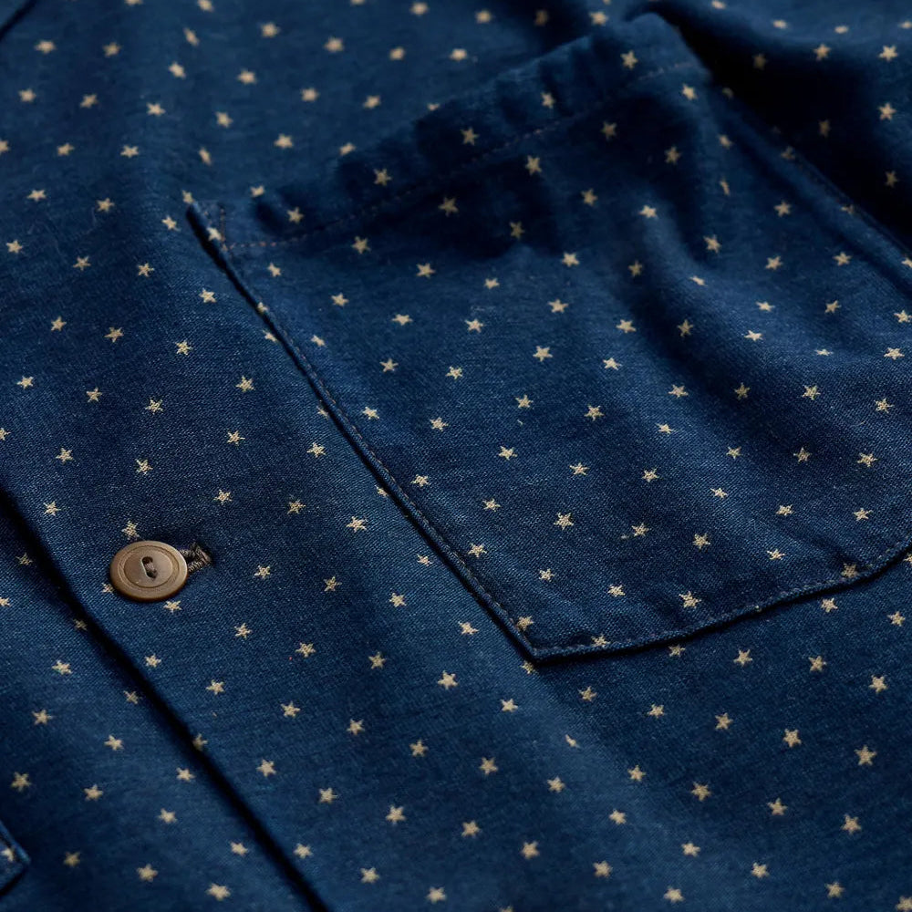 Close-up of a dark blue button-up shirt with a small beige star pattern and a chest pocket.