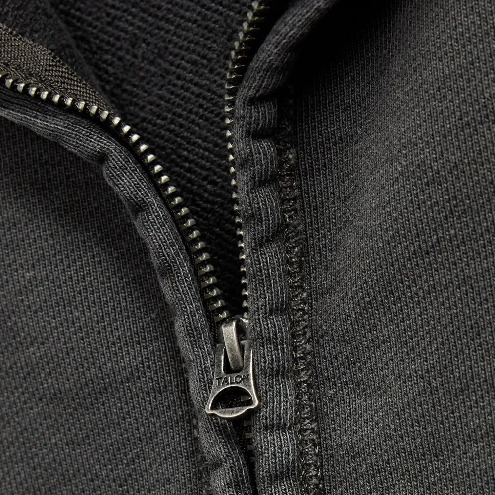 Close-up of a dark gray zippered knit garment, showing the zipper pull and ribbed fabric texture.