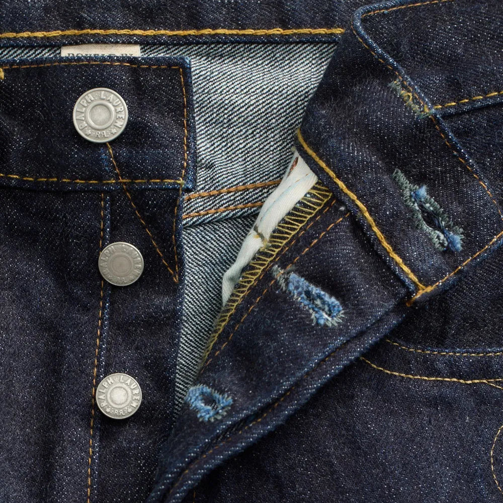 Close-up of a dark blue denim jacket with buttons and floral embroidery.