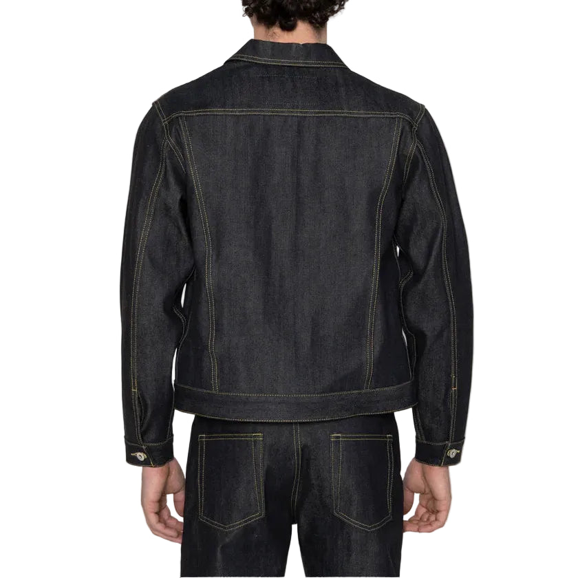 A man viewed from the back wearing a dark indigo denim jacket and matching dark jeans against a plain white background.
