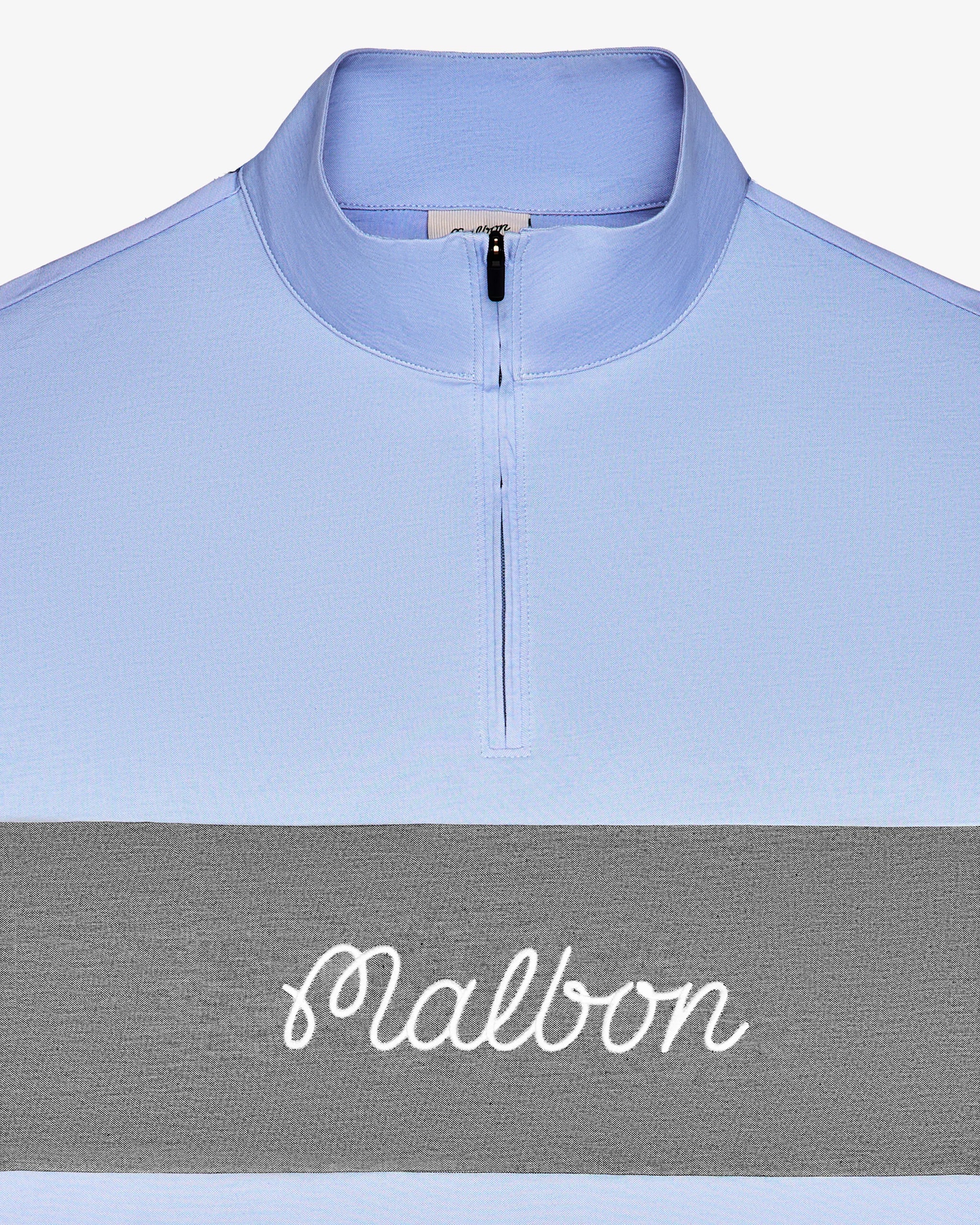 A close-up of a light blue quarter-zip pullover with a wide gray horizontal stripe across the chest and the word 'Malbon' in white script.