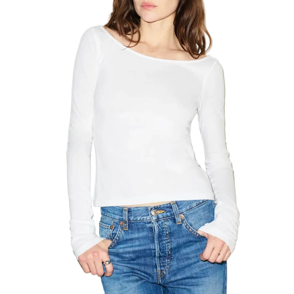 Woman wearing a white long-sleeve top and blue jeans against a white background