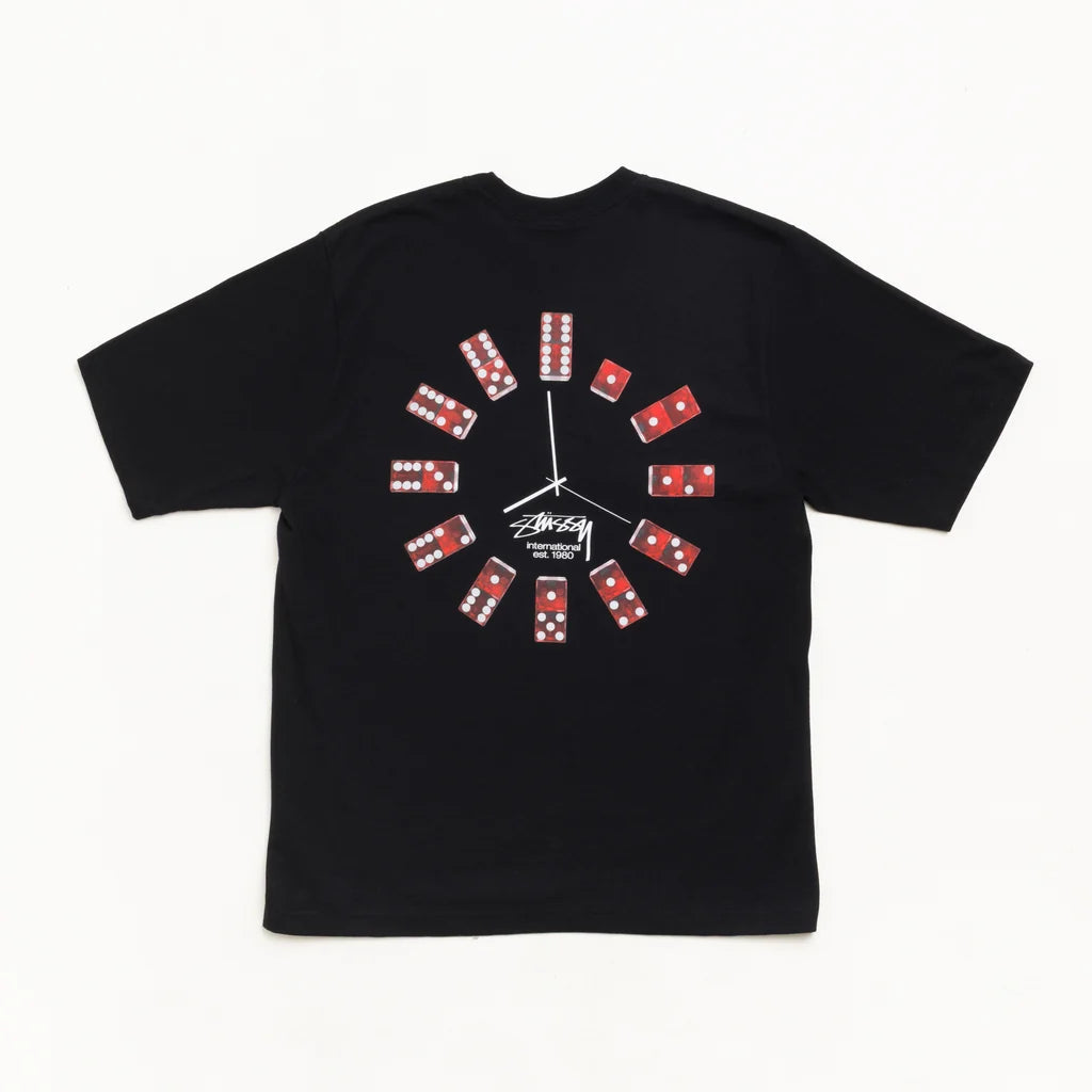 A black short-sleeve t-shirt featuring a graphic design of dominoes arranged in a clock face on the chest, with a white Stussy logo printed below the center graphic.