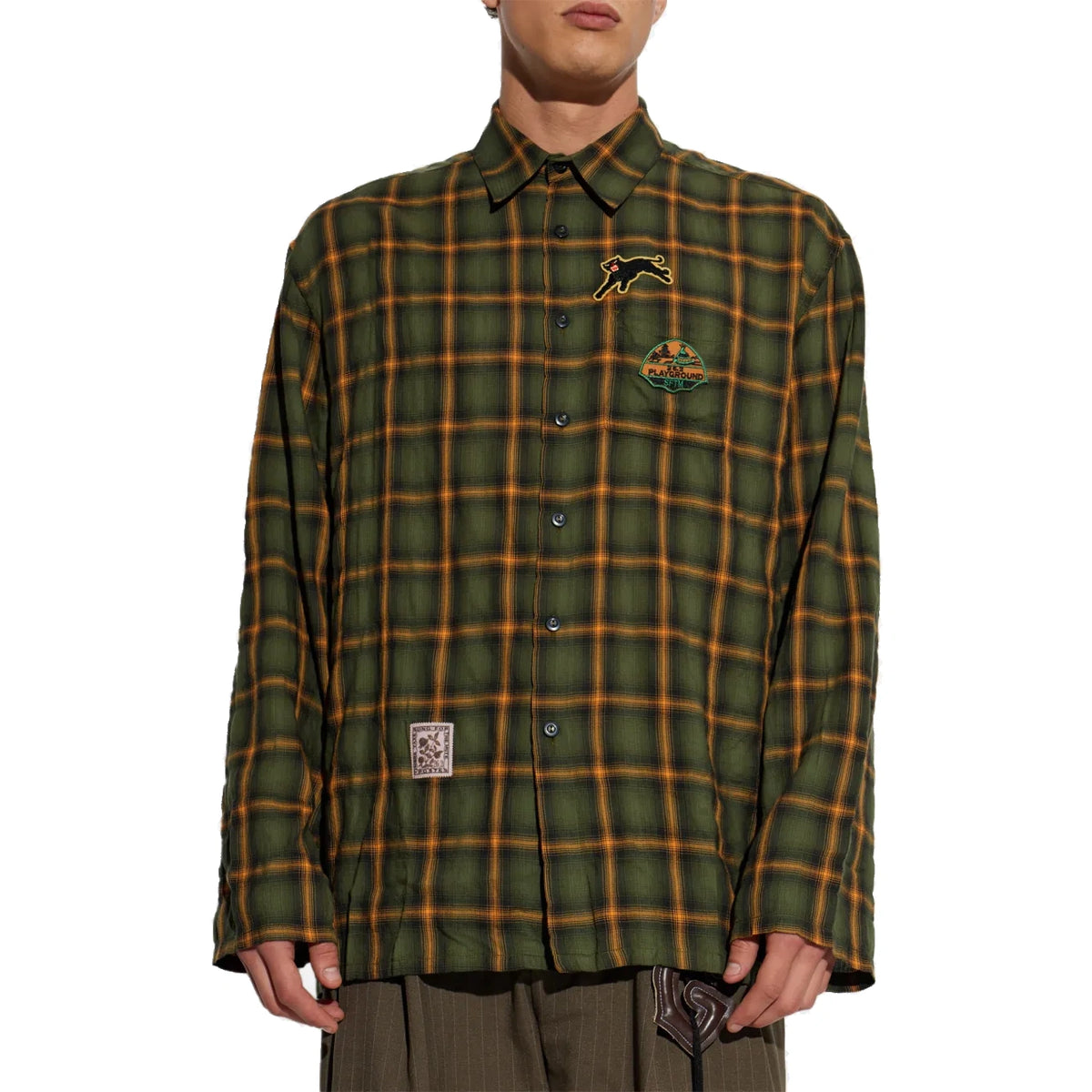 A model wears the School Shirt buttoned, showing the relaxed fit, the chest patches and a woven label patch at the lower front.