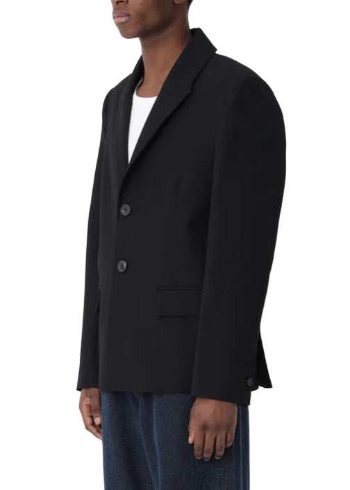 Man wearing a black blazer and blue pants on a white background