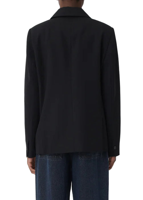 Person wearing a black jacket and dark pants on a white background