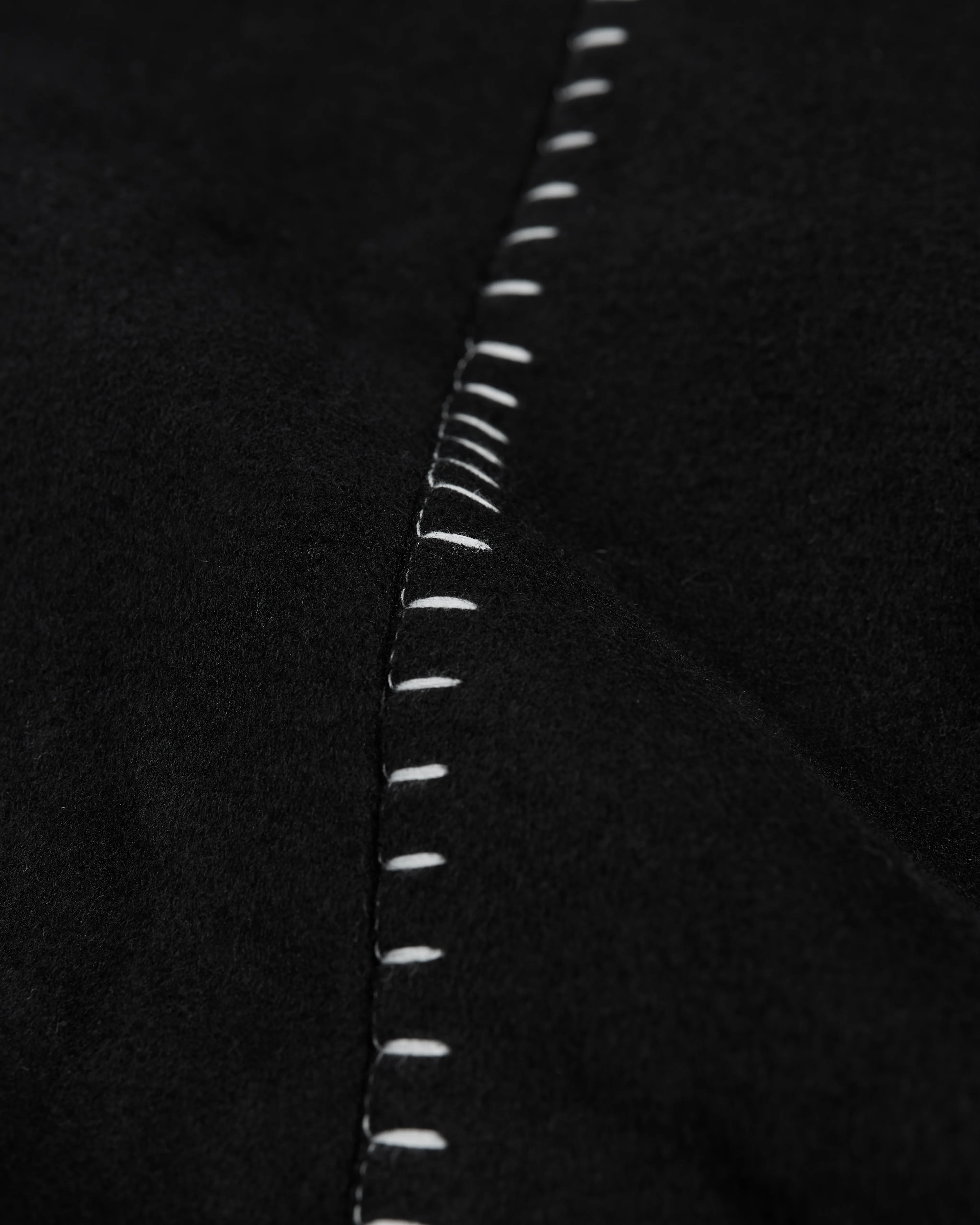 Close-up of white stitching on black fabric