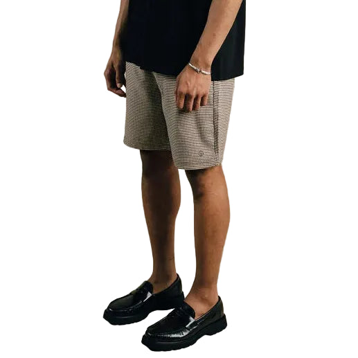 Man wearing a black t-shirt with text and beige shorts on a plain background
