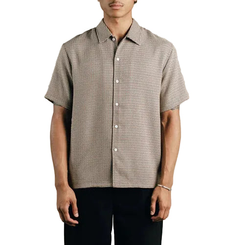 Man wearing a patterned shirt and black pants on a white background