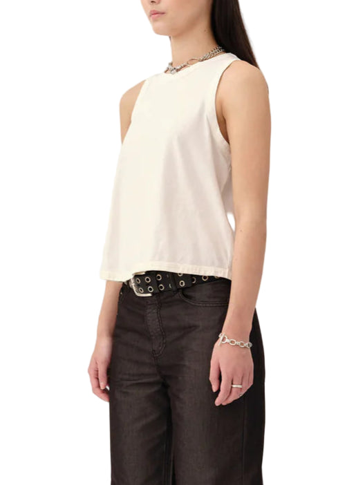Woman wearing a white sleeveless top and dark pants on a white background