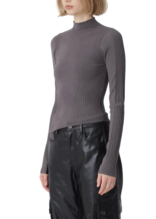 Woman wearing a gray ribbed sweater and black leather pants on a white background