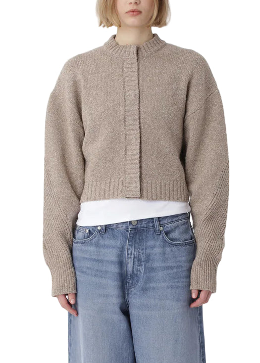 Person wearing a beige sweater and blue jeans on a white background